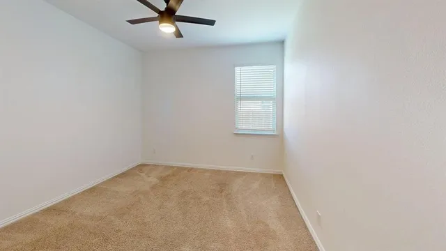 an empty room with a window and a fan