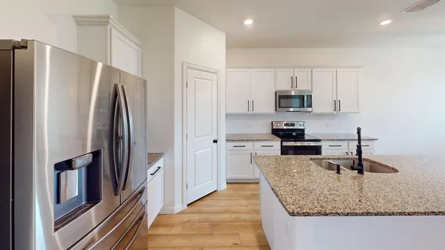 a kitchen with stainless steel appliances granite countertop a refrigerator a stove and a sink