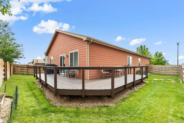 a view of a house with a yard and a wooden deck