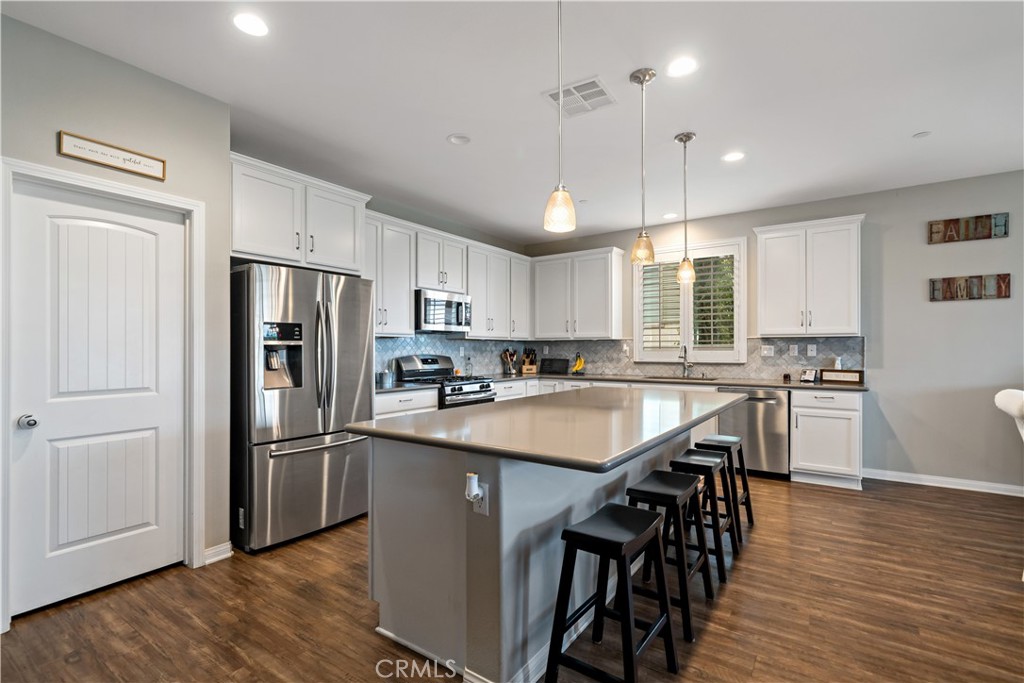 30640 Lone Pine Drive Menifee, CA 92584 - Photo 13 of 48 a kitchen with stainless steel appliances granite countertop a refrigerator a sink dishwasher a stove and white cabinets with wooden floor