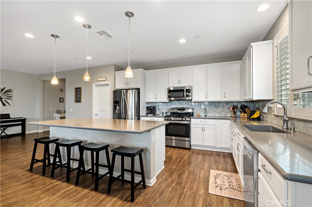 30640 Lone Pine Drive Menifee, CA 92584 - Photo 17 of 48 a large kitchen with kitchen island a stove a sink a dining table and chairs