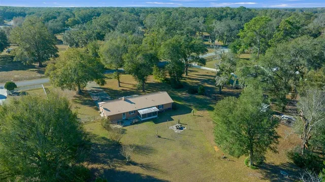 an aerial view of a house with a yard and large trees
