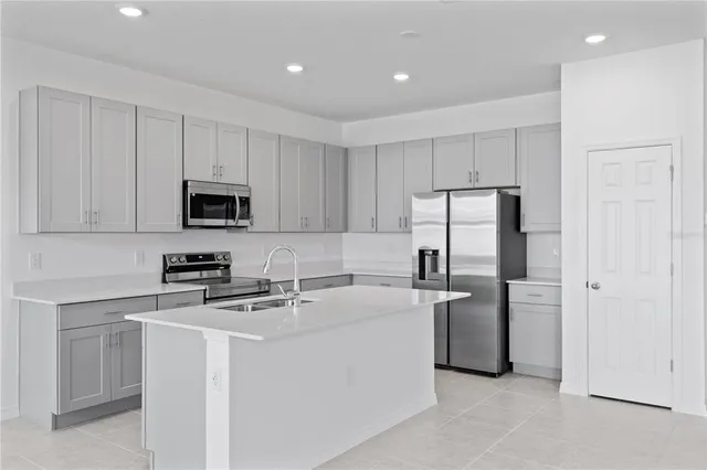 a kitchen with stainless steel appliances granite countertop a refrigerator stove a sink and white cabinets