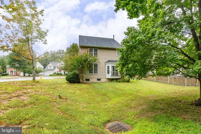 a yellow house with a big yard plants and large trees