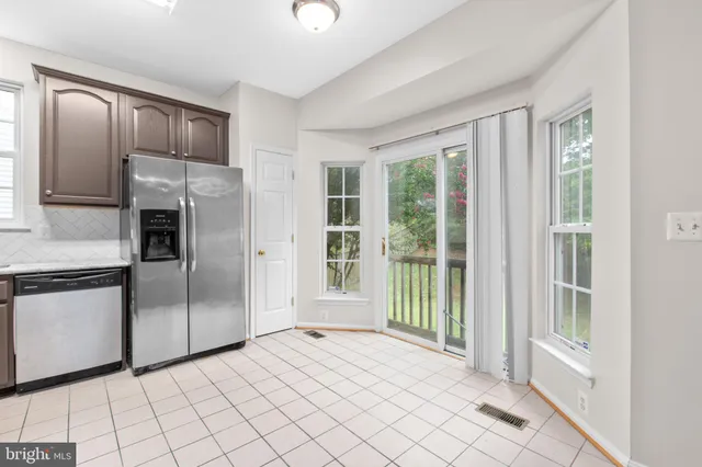 a view of a refrigerator in kitchen and an empty room
