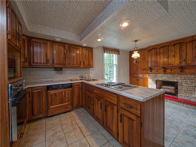 This spacious kitchen features a custom stone fireplace, walnut cabinetry, a casual dining area and generous counter space.