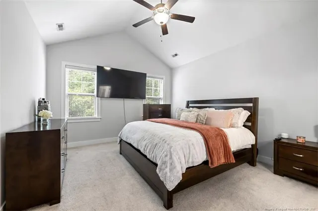 a bedroom with a bed window and a flat tv screen on a dresser