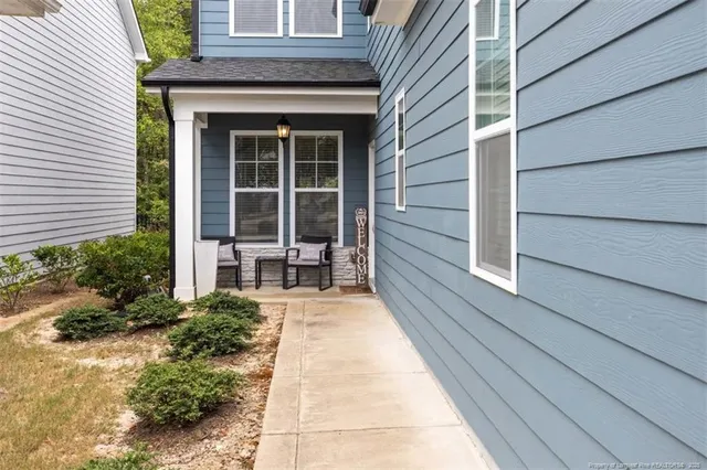 a balcony with table and chairs and potted plants