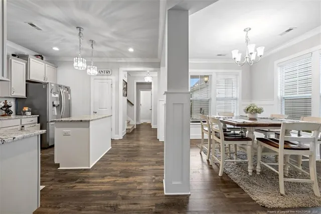 a kitchen with stainless steel appliances kitchen island granite countertop a table chairs sink and cabinets