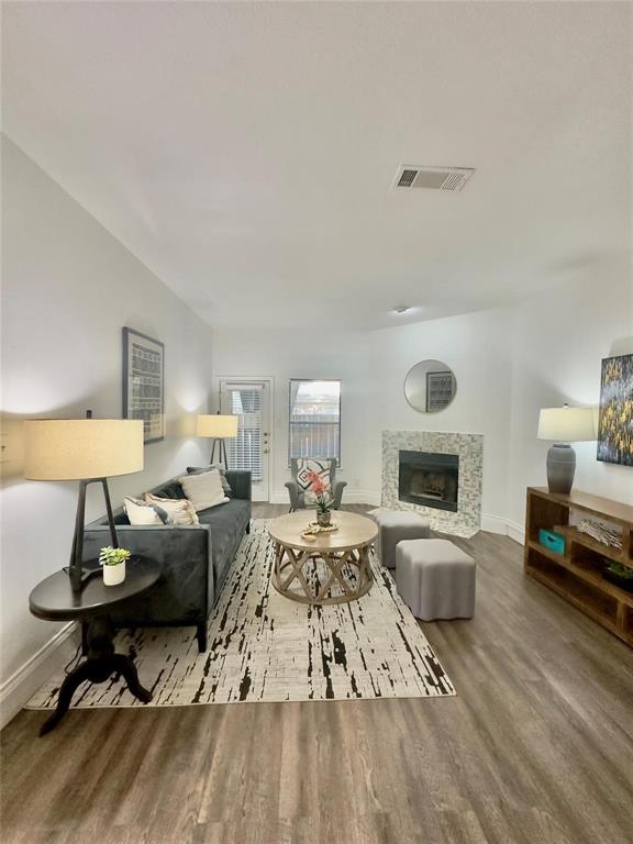 7340 Skillman Street, Unit 405 Dallas, TX 75231 - Photo 2 of 18 Spacious living area featuring wood-finish flooring, a tiled fireplace, and a glass-paned exterior door