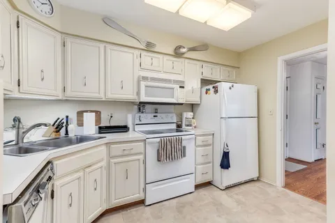 a kitchen with white cabinets and white appliances