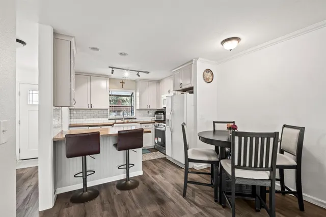 a kitchen with stainless steel appliances kitchen island a table chairs in it and wooden floors
