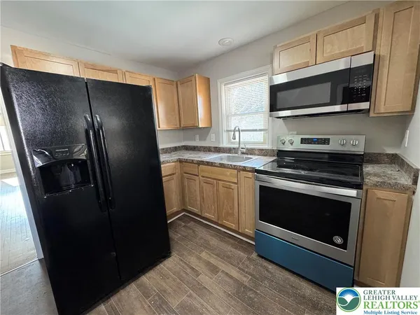 a kitchen with stainless steel appliances kitchen island granite countertop a refrigerator stove and microwave