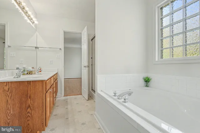 a bathroom with a granite countertop tub sink and mirror