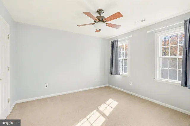 an empty room with window and ceiling fan