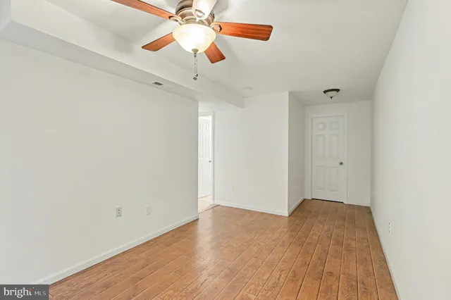 a view of a room with wooden floor and a ceiling fan