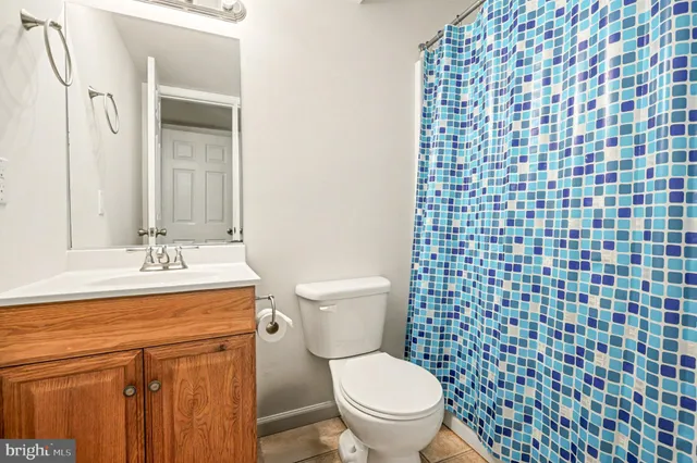 a bathroom with a granite countertop toilet a sink a mirror and a shower