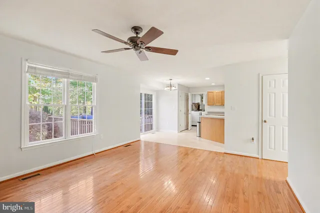 a view of a big room with wooden floor a ceiling fan and windows
