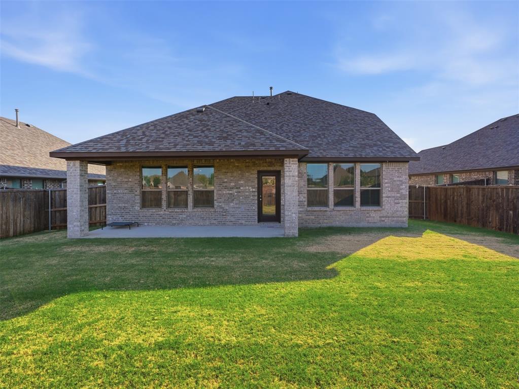 1128 Red Hawk Lane Forney, TX 75126 - Photo 35 of 37 Expansive backyard with a covered patio, brick exterior, multiple windows, and a wood privacy fence