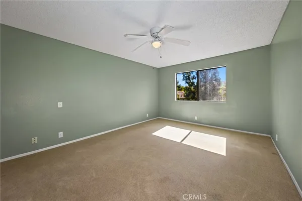 an empty room with windows and ceiling fan