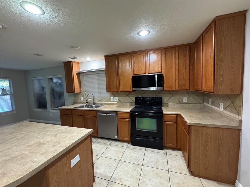 10608 Colfax Drive McKinney, TX 75072 - Photo 7 of 21 a kitchen with stainless steel appliances granite countertop wooden cabinets a stove top oven a sink and dishwasher