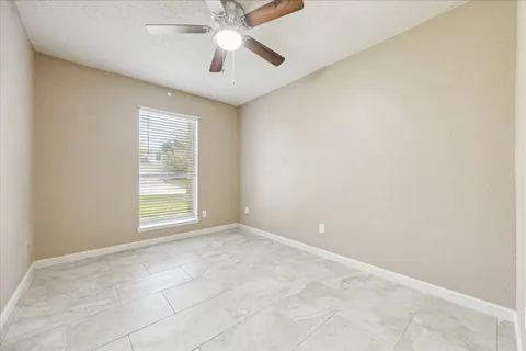 an empty room with windows and fan
