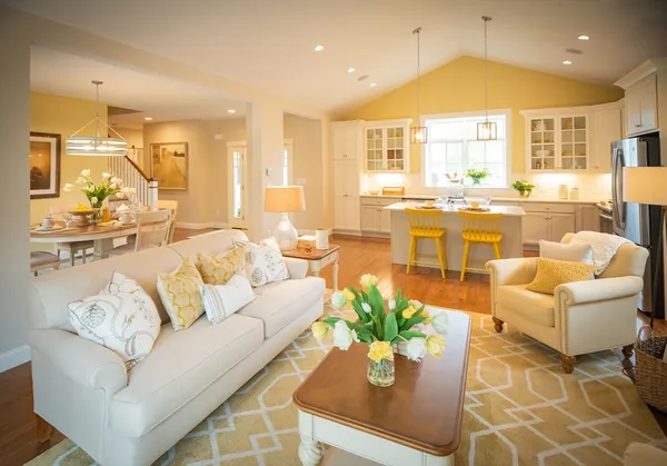 a living room with furniture kitchen view and large windows