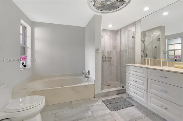 a spacious bathroom with a bathtub shower sink mirror and toilet