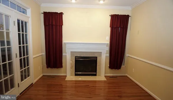 a view of an empty room with wooden floor and a fireplace