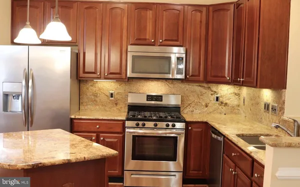 a kitchen with stainless steel appliances granite countertop a sink stove and refrigerator