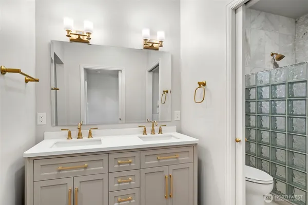 a bathroom with a double vanity sink toilet and mirror