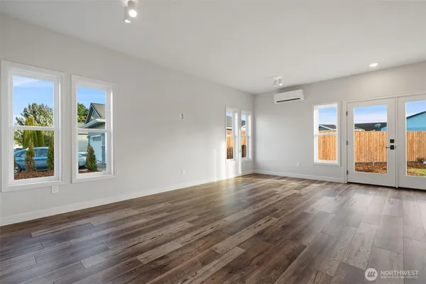 a view of an empty room with window and wooden floor