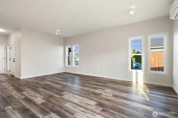 a view of an empty room with window and wooden floor