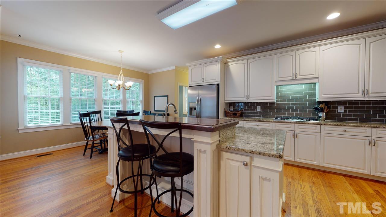 8005 Millenium Drive Raleigh, NC 27614 - Photo 8 of 30 a kitchen with stainless steel appliances granite countertop a stove a refrigerator a microwave a dining table and chairs with wooden floor