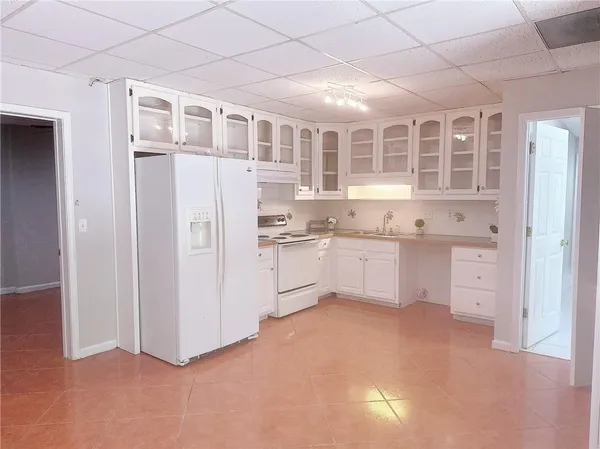 a kitchen with white cabinets and wooden floor