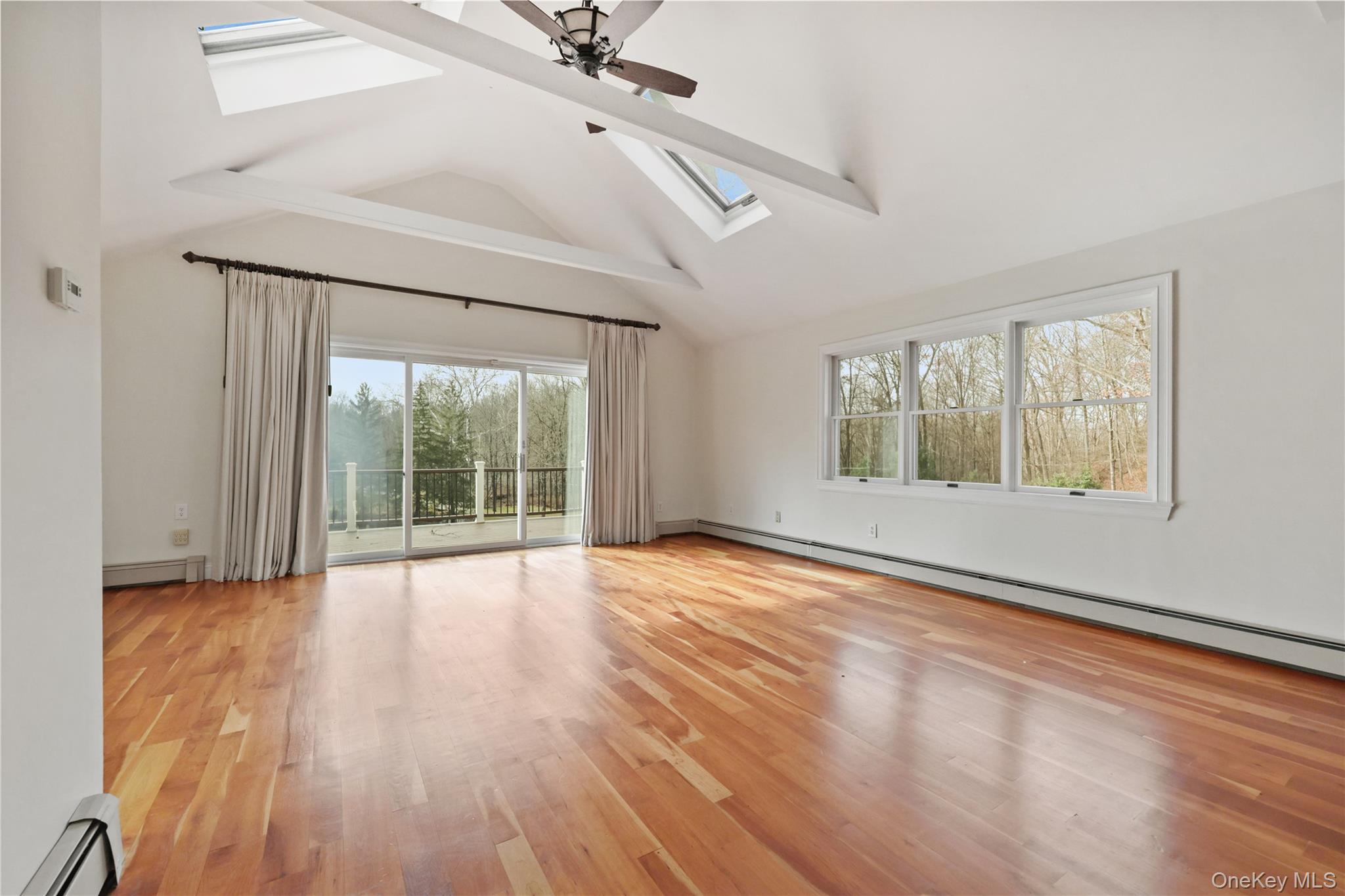 353 Turk Hill Road Brewster, NY 10509 - Photo 19 of 31 Great room featuring a skylight, a baseboard heating unit, light wood-style floors, ceiling fan, and beamed ceiling