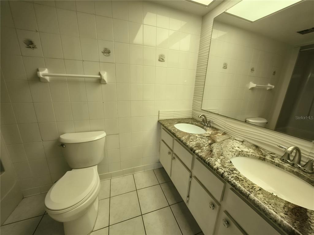 4518 Garnet Drive, Unit 202 New Port Richey, FL 34652 - Photo 30 of 66 a bathroom with a granite countertop toilet a sink and mirror