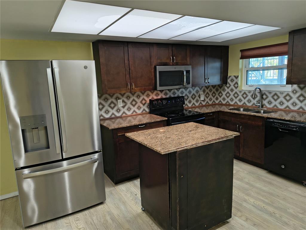4518 Garnet Drive, Unit 202 New Port Richey, FL 34652 - Photo 3 of 66 a kitchen with granite countertop a refrigerator and a stove top oven