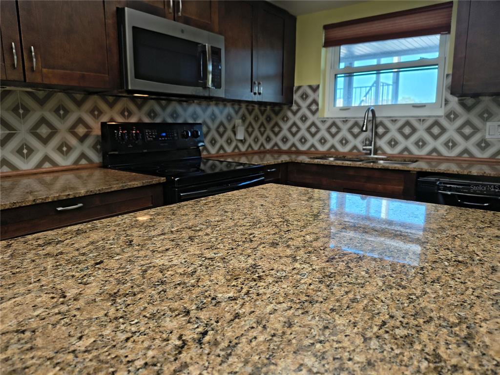 4518 Garnet Drive, Unit 202 New Port Richey, FL 34652 - Photo 10 of 66 a kitchen with granite countertop white cabinets and black appliances