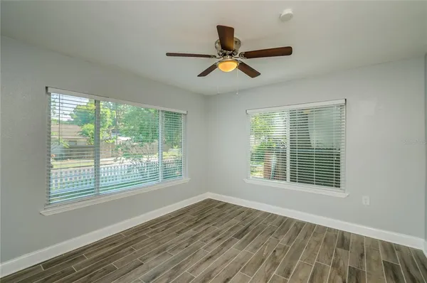 a view of an empty room with wooden floor and a window