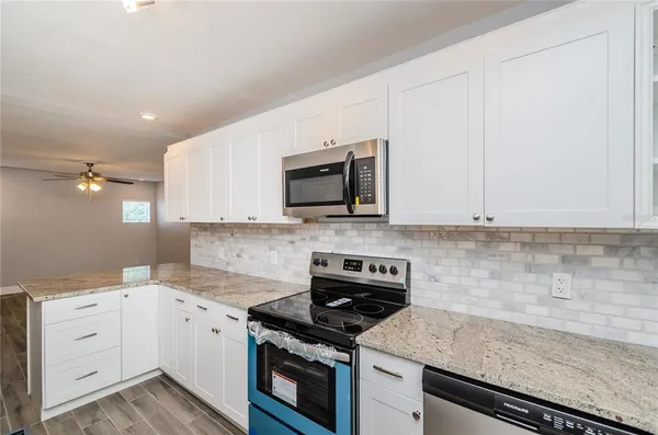 a kitchen with granite countertop white cabinets and white appliances
