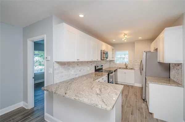 a large white kitchen with a refrigerator a sink dishwasher and a stove with wooden floor