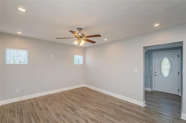 an empty room with wooden floor mirror and windows