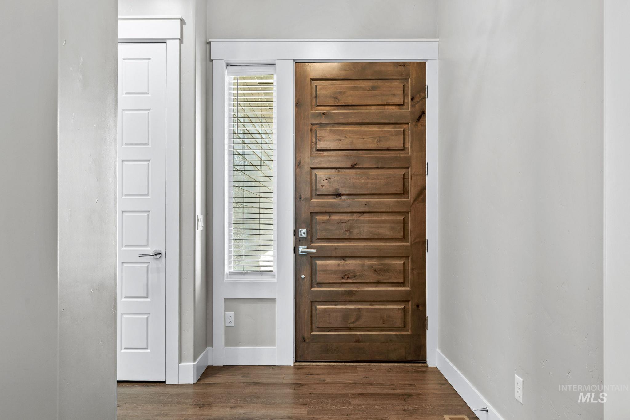2934 East Murchison Street Meridian, ID 83642 - Photo 6 of 44 Entryway featuring a panel door with a rich wood finish, a vertical sidelight with blinds, and durable wood-finish flooring
