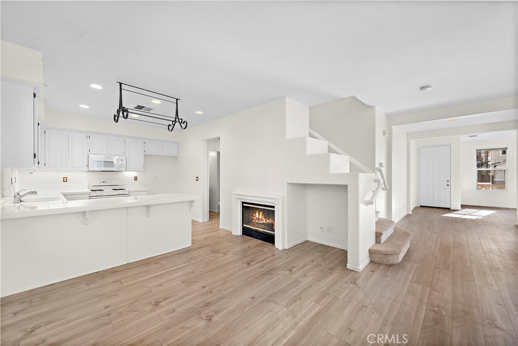 68 Kyle Court Ladera Ranch, CA 92694 - Photo 11 of 33 a large white kitchen with a refrigerator a stove a sink dishwasher and a fireplace with wooden floor