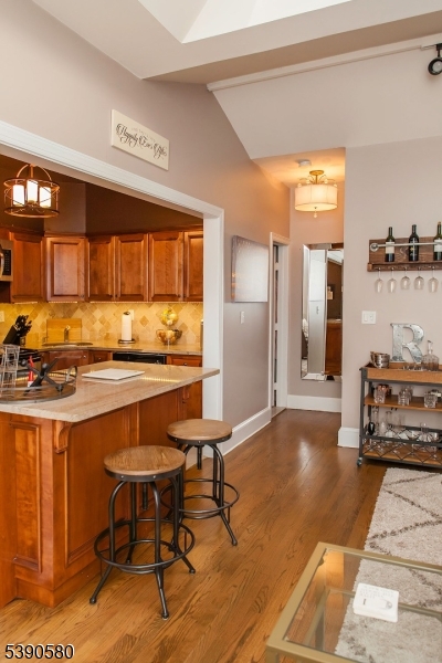 309 1st Street, Unit 3C Hoboken, NJ 07030 - Photo 5 of 12 a kitchen with stainless steel appliances kitchen island granite countertop a table chairs in it and wooden floors