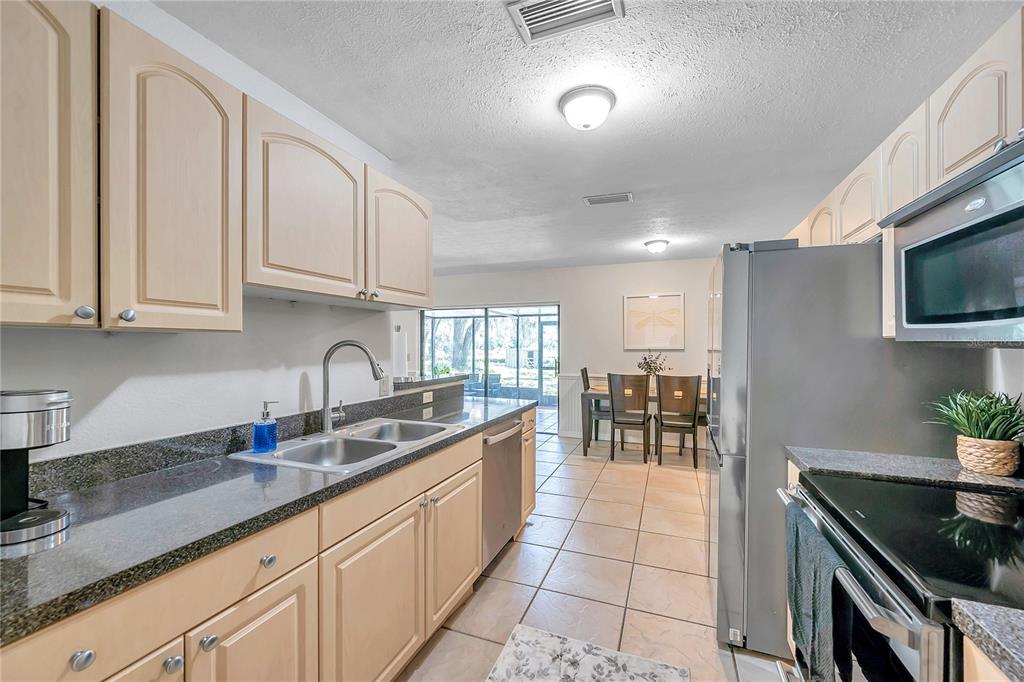 7405 Williams Road Seffner, FL 33584 - Photo 26 of 100 a kitchen with stainless steel appliances granite countertop a sink a stove counter space and cabinets