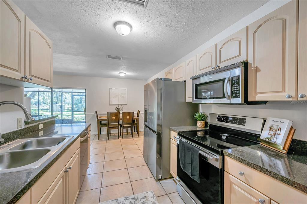 7405 Williams Road Seffner, FL 33584 - Photo 27 of 100 a kitchen with granite countertop a stove a sink and a microwave