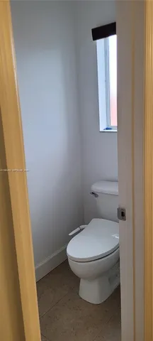 a white toilet sitting next to a small window