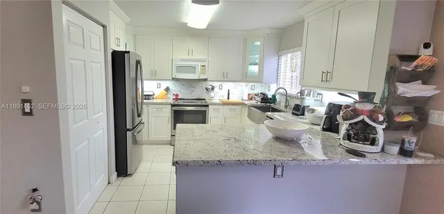 a kitchen with stainless steel appliances granite countertop a sink refrigerator and cabinets